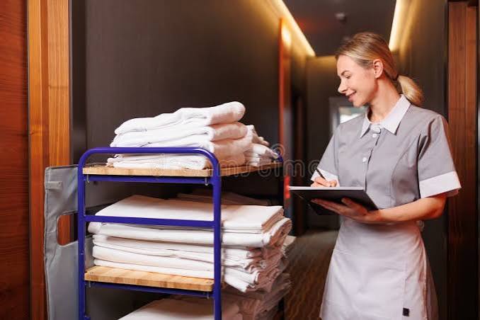 Professional hotel housekeeper making a guest room bed